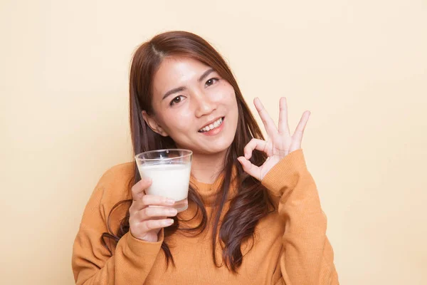 喝一杯牛奶的健康亚洲女人显示 Ok 的手势. — 图库照片