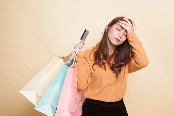 Ongelukkige jonge Aziatische vrouw met shopping tassen en credit card. — Stockfoto