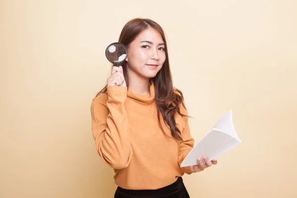 Asian woman with a book and magnifying glass. — Stock Photo, Image