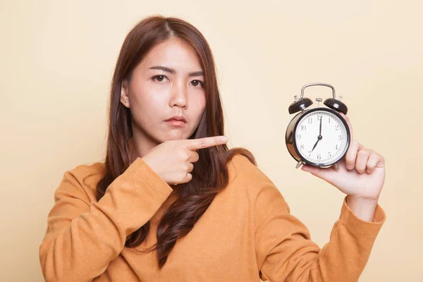 Boos jonge Aziatische vrouw punt aan een klok. — Stockfoto