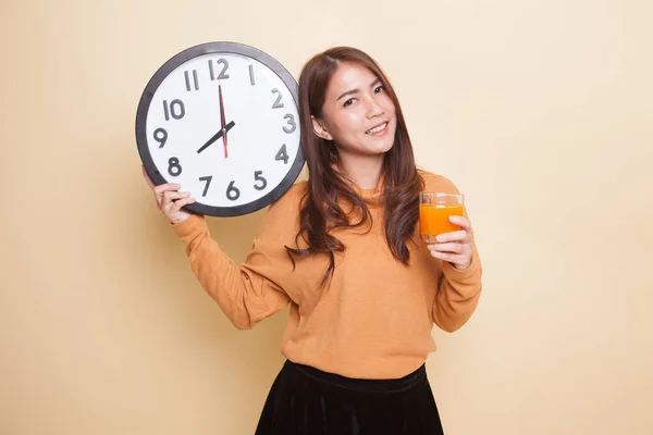 Mujer asiática con un reloj beber jugo de naranja . — Foto de Stock