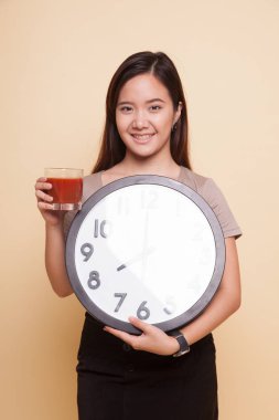 Domates suyu ve saat ile genç Asyalı kadın.