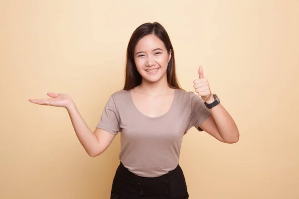 Hermosa joven asiática mostrar la palma de la mano y pulgares hacia arriba . —  Fotos de Stock