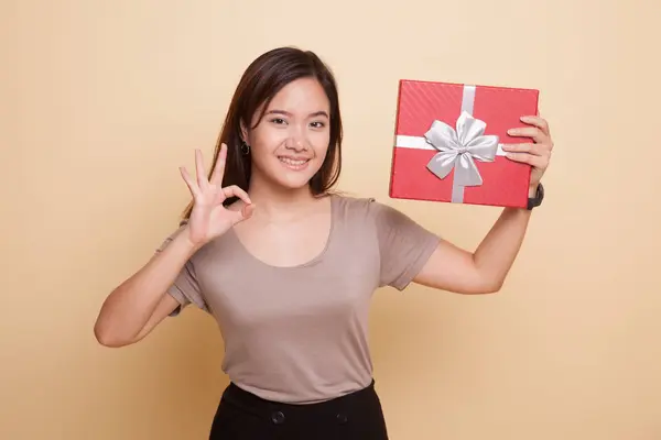 Giovane donna asiatica mostra OK con una scatola regalo . — Foto Stock