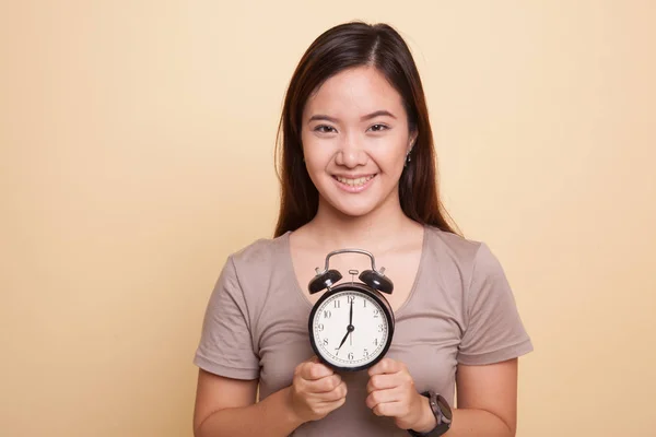 Jonge Aziatische vrouw glimlach met een klok. — Stockfoto