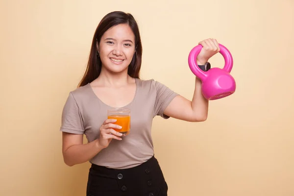 Giovane donna asiatica con kettlebell bere succo d'arancia . — Foto Stock