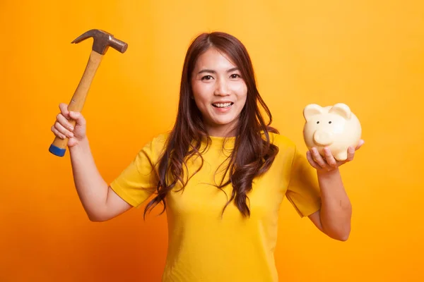 Asian woman with pig coin bank and hammer. — Stock Photo, Image