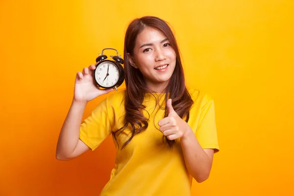 Young Asian woman show thumbs up with a clock in yellow dress — Stock Photo, Image