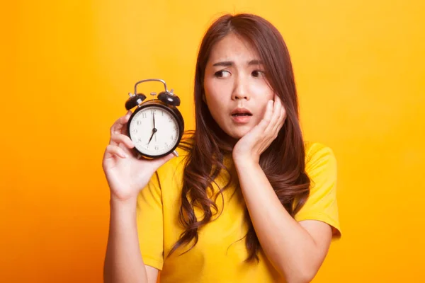 Young Asian woman is stressed with a clock in yellow dress — Stock Photo, Image