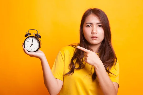 Rozhněvaný mladý asijských žena přejděte na hodiny ve žlutých šatech — Stock fotografie