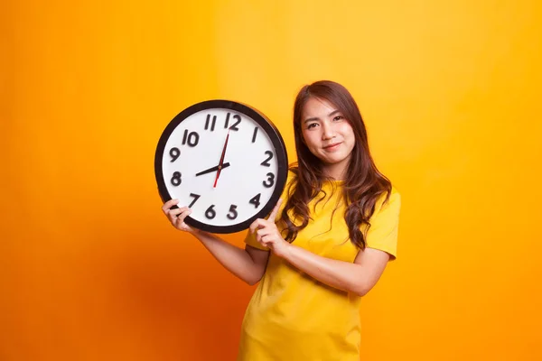 Jovem mulher asiática com um relógio em vestido amarelo — Fotografia de Stock