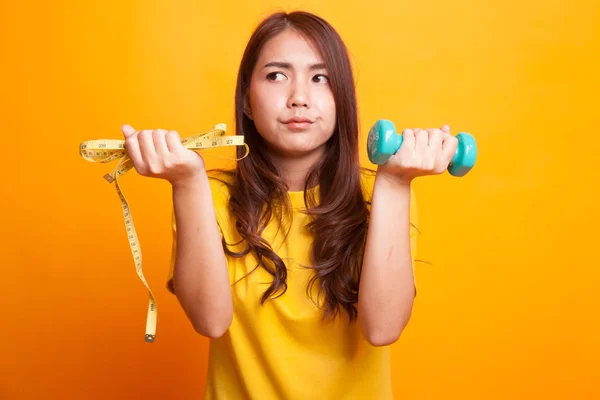 Uitgeput Aziatische vrouw met halters en meetlint in yell — Stockfoto