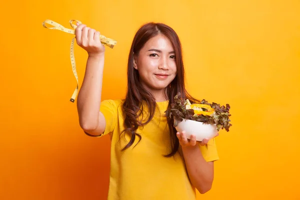 Mujer asiática sana con cinta métrica y ensalada en amarillo dre — Foto de Stock