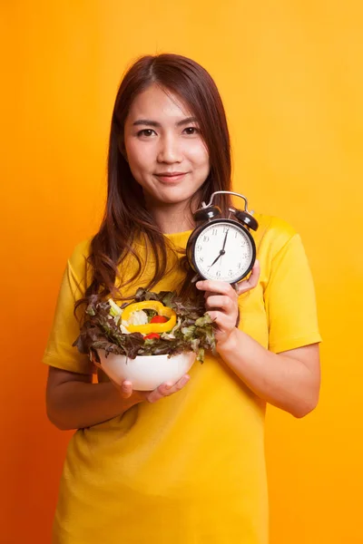 Jonge Aziatische vrouw met klok en salade in gele jurk — Stockfoto