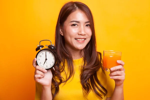 Ázsiai nő, egy óra narancs ital gyümölcslé sárga ruha — Stock Fotó