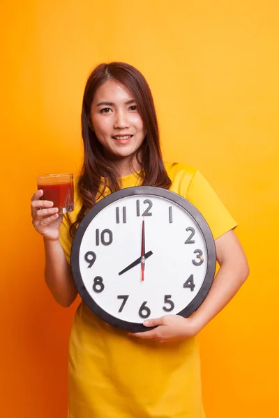 Mladá asijská žena s rajčatovou šťávu a hodiny ve žlutých šatech — Stock fotografie