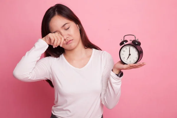 Sleepy jonge Aziatische vrouw met een klok in de ochtend. — Stockfoto