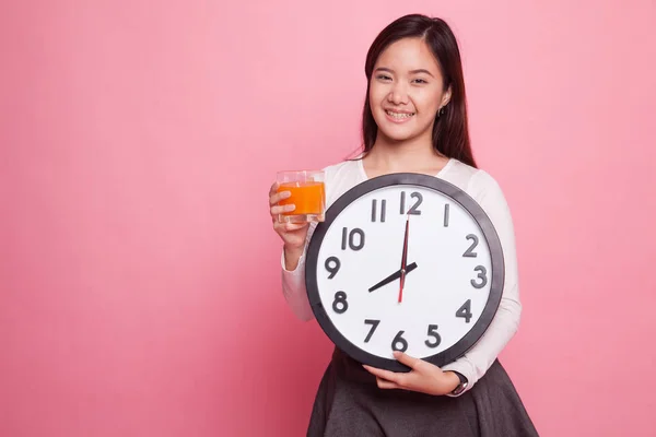 Asijská žena s hodinami pít pomerančový džus. — Stock fotografie