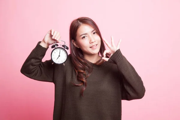 Young Asian woman show OK with a clock. — Stock Photo, Image