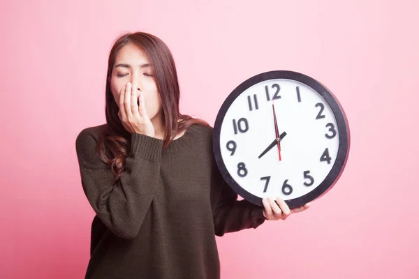 Sleepy jonge Aziatische vrouw met een klok in de ochtend. — Stockfoto