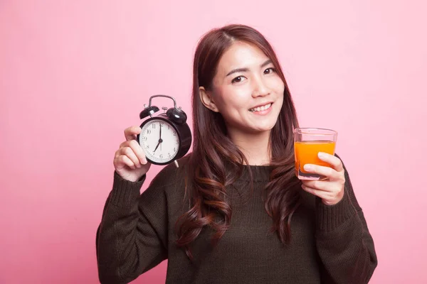 Asijská žena s hodinami pít pomerančový džus. — Stock fotografie