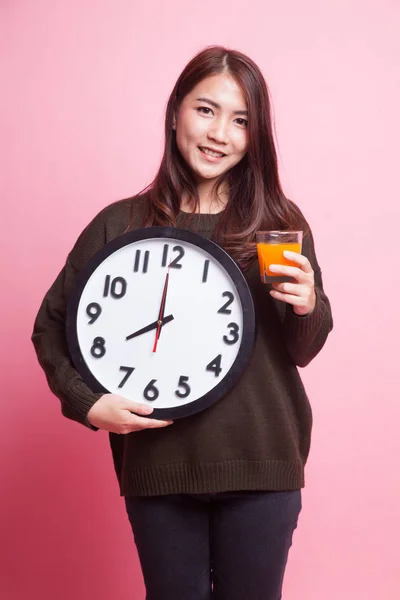 亚裔女子和时钟喝桔子汁. — 图库照片