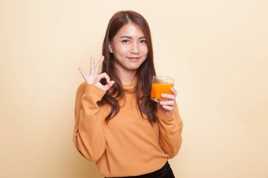 Genç Asyalı kadın içki portakal suyu göster Ok işareti.