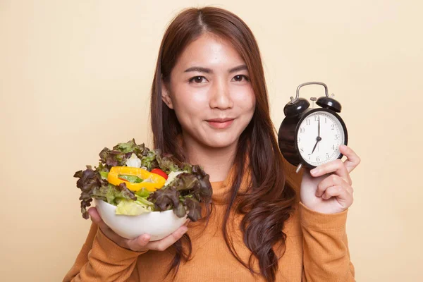 Jonge Aziatische vrouw met klok en salade. — Stockfoto