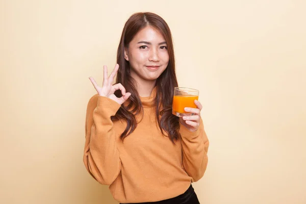 Jonge Aziatische vrouw drankje oranje sap Ok teken weergeven. — Stockfoto