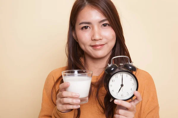 Gesunde asiatische Frau trinkt Glas Milch halten Uhr. — Stockfoto