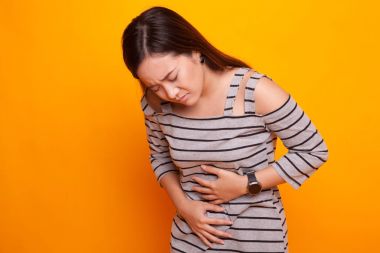 Genç Asyalı kadın mide ağrısı var.