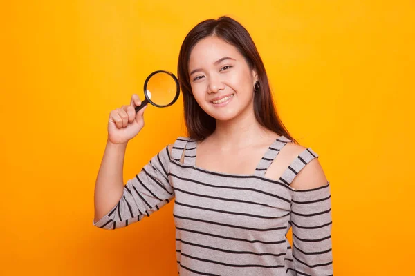 Young Asian woman with a magnifying glass. — Stock Photo, Image