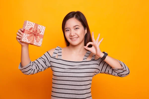 Young Asian woman show OK with a gift box. — Stock Photo, Image