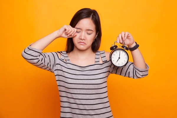 Sömnig ung asiatisk kvinna med en klocka på morgonen. — Stockfoto
