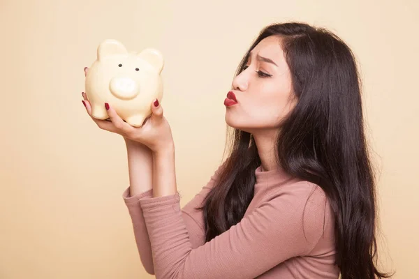 Jovem mulher asiática beijar um banco de moedas rosa . — Fotografia de Stock