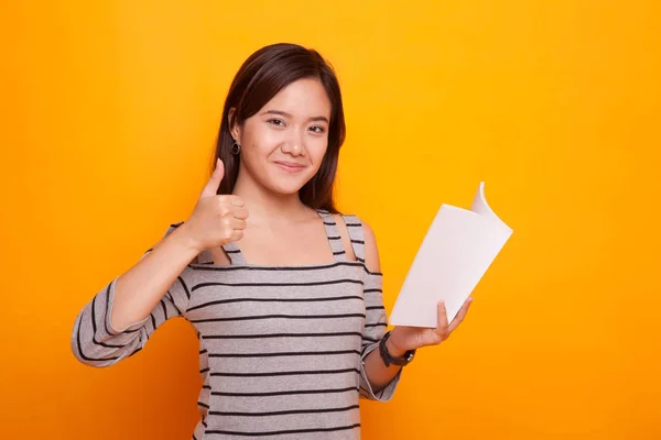 Jonge Aziatische vrouw duimen omhoog met een boek. — Stockfoto