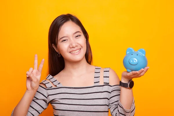 Asian woman show victory sign with pig coin bank. — Stock Photo, Image