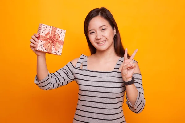 Ασιατικές γυναίκα δείξει σήμα της νίκης με ένα κουτί δώρου. — Φωτογραφία Αρχείου