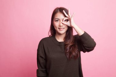 Güzel genç Asyalı kadın göster Tamam gözü üzerinde oturum.