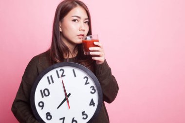 Domates suyu ve saat ile genç Asyalı kadın.