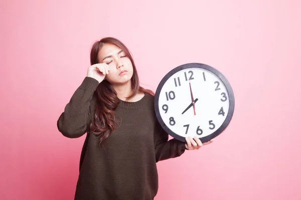 Sleepy young Asian woman with a clock in the morning. — Stock Photo, Image