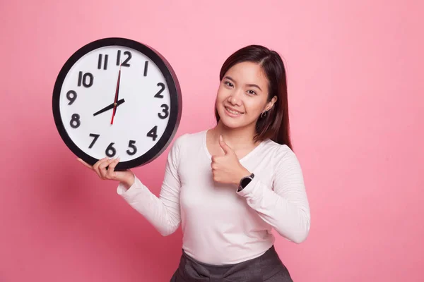 Ung asiatisk kvinna tummen upp med en klocka. — Stockfoto