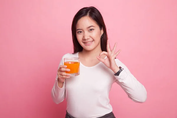 Giovane donna asiatica bere succo d'arancia spettacolo OK segno . — Foto Stock