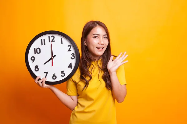 Gelukkig jonge Aziatische vrouw met een klok in gele jurk — Stockfoto