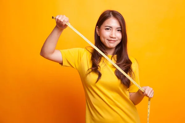 Jonge Aziatische vrouw met meetlint in gele jurk — Stockfoto