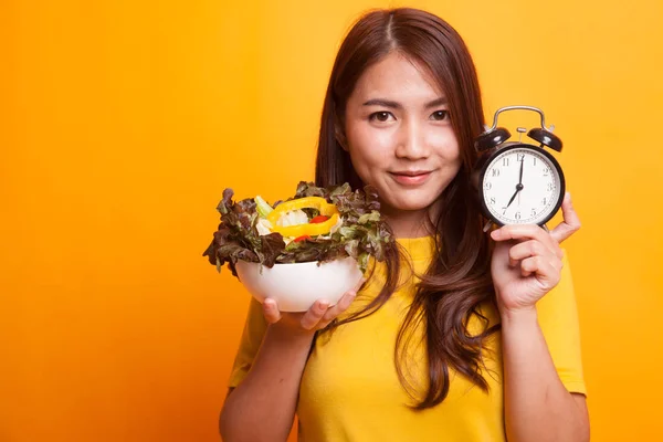 年轻的亚洲妇女与时钟和沙拉在黄色礼服 — 图库照片