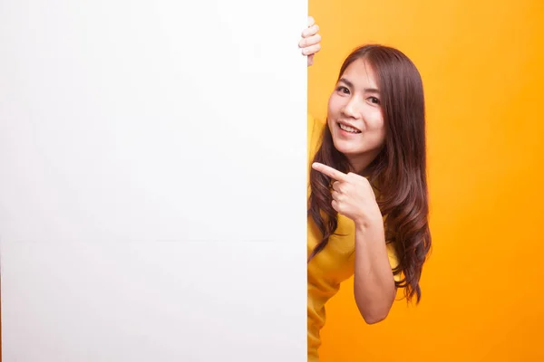 Mujer asiática joven señala un signo en blanco en vestido amarillo —  Fotos de Stock