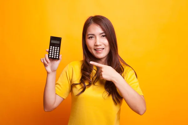 Азиатка указывает на калькулятор в желтом платье — стоковое фото