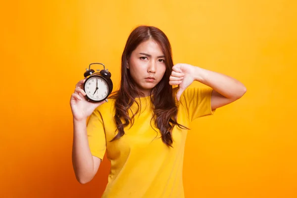 Jeune femme asiatique pouces vers le bas avec une horloge en robe jaune — Photo