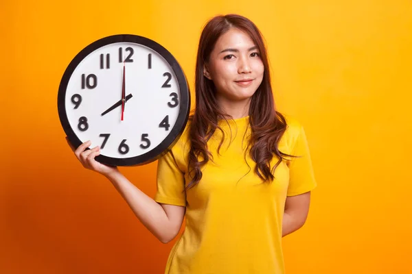 Jovem mulher asiática com um relógio em vestido amarelo — Fotografia de Stock